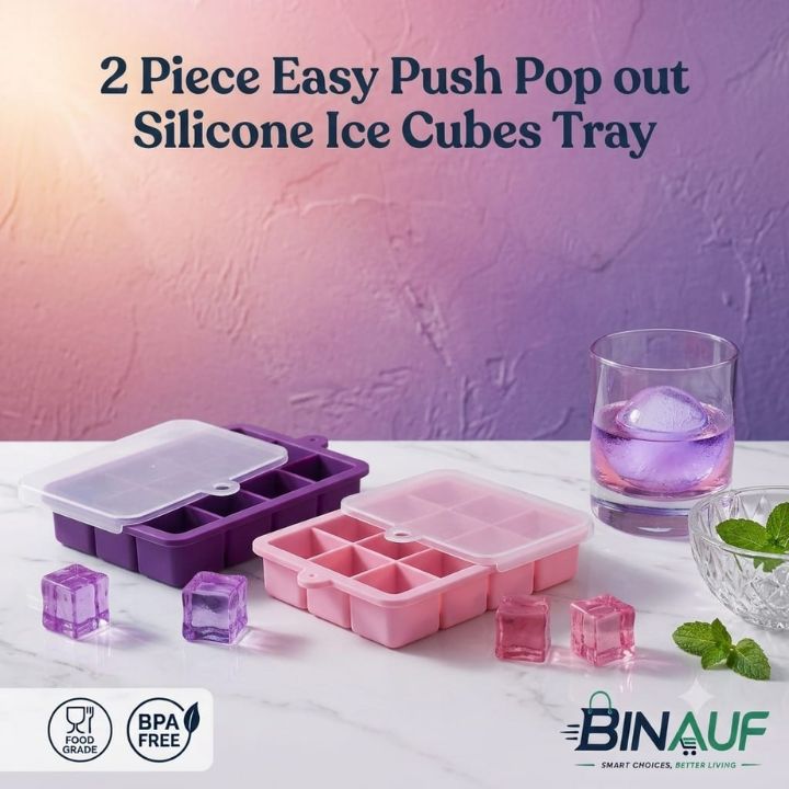 Two silicone ice cube trays in purple and pink are displayed on a white marble surface with ice cubes and a glass of purple liquid. The background is a textured purple wall with promotional text at the top and the BINAUF logo at the bottom right.
