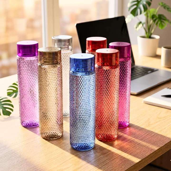 Colorful textured Tenta water bottles on a desk with a laptop and plants in the background